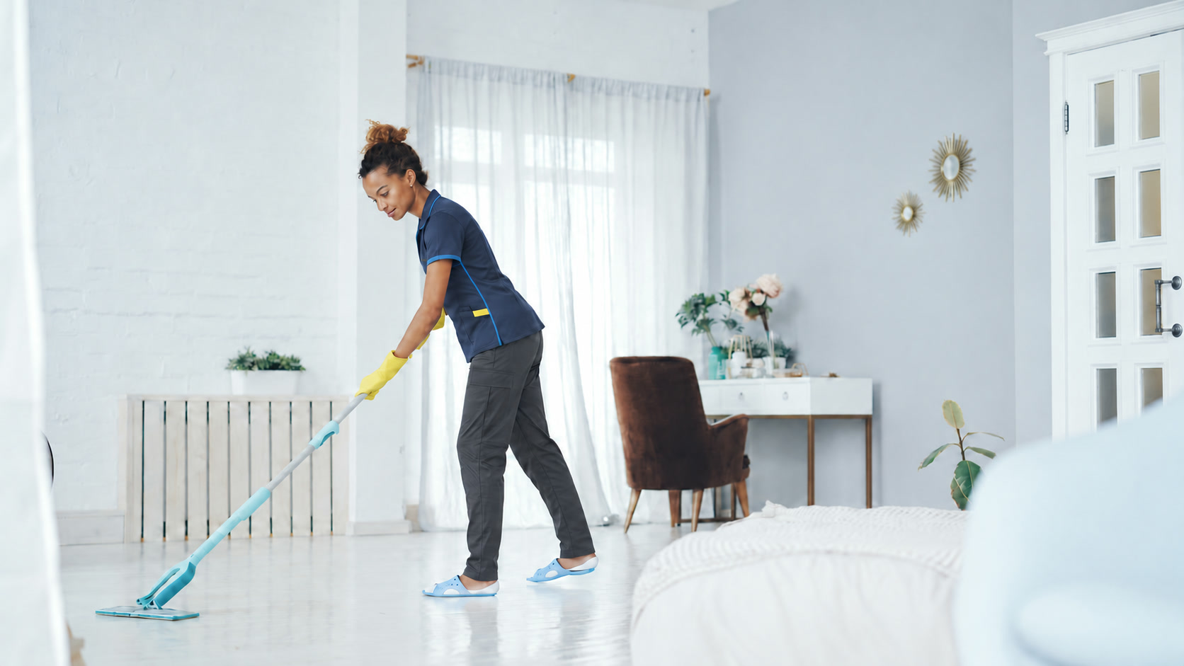 Uniformed cleaner mopping a bright home floor