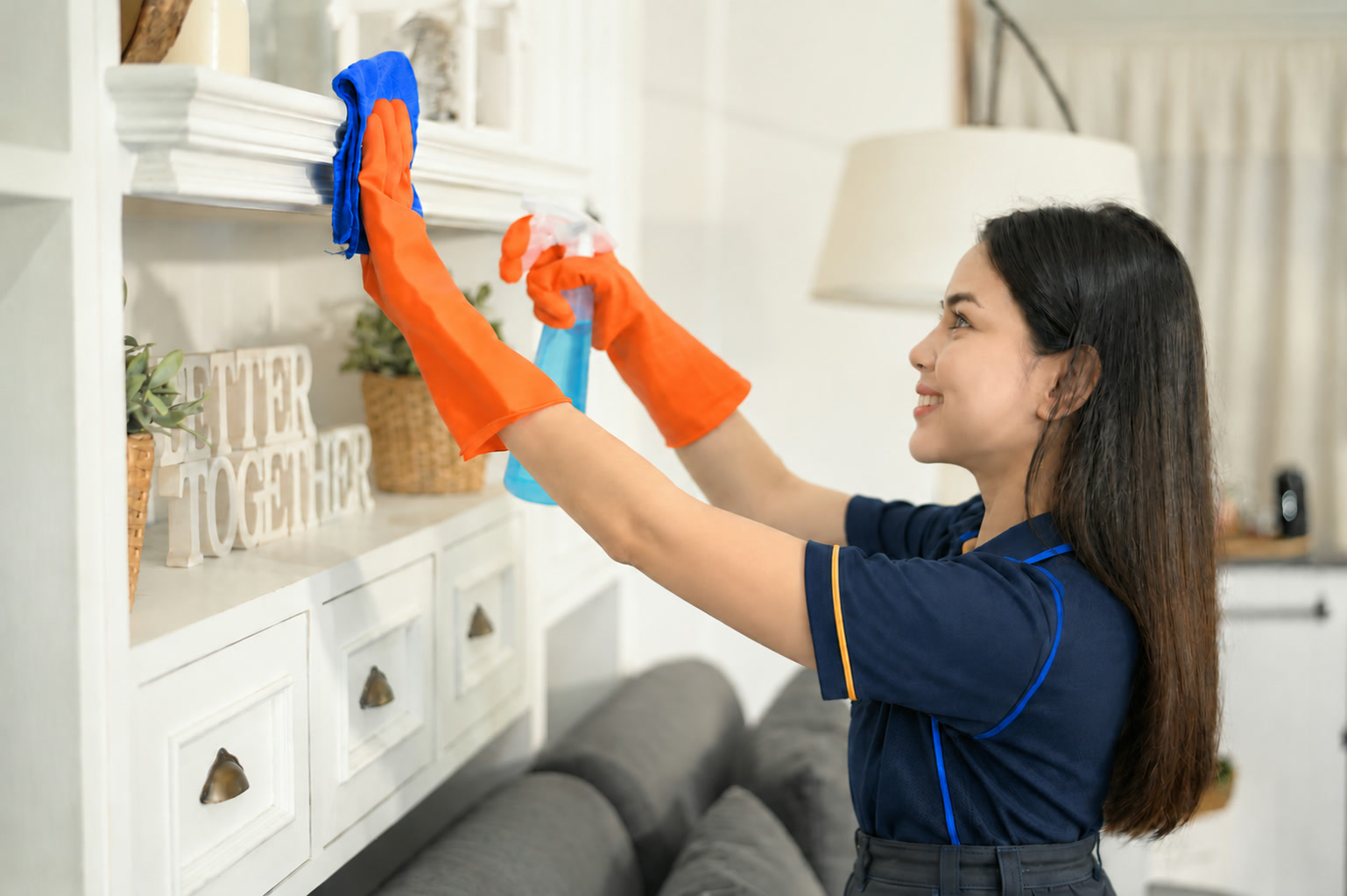 Uniformed cleaner detailing shelves and cabinetry