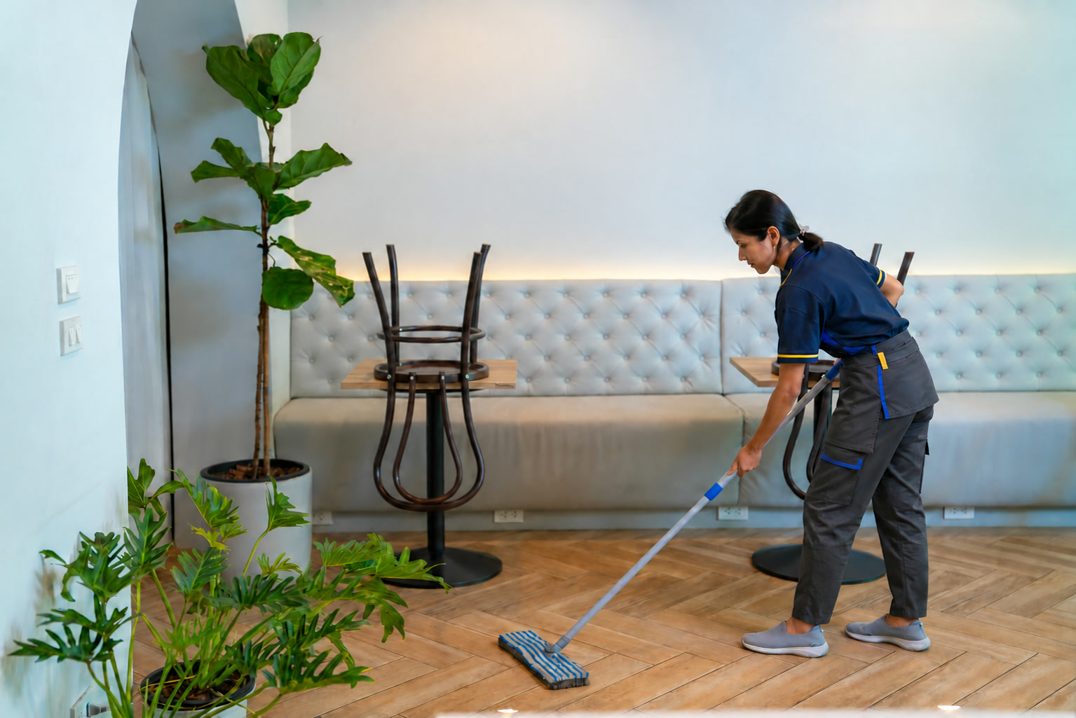 Uniformed cleaner working in a restaurant dining area